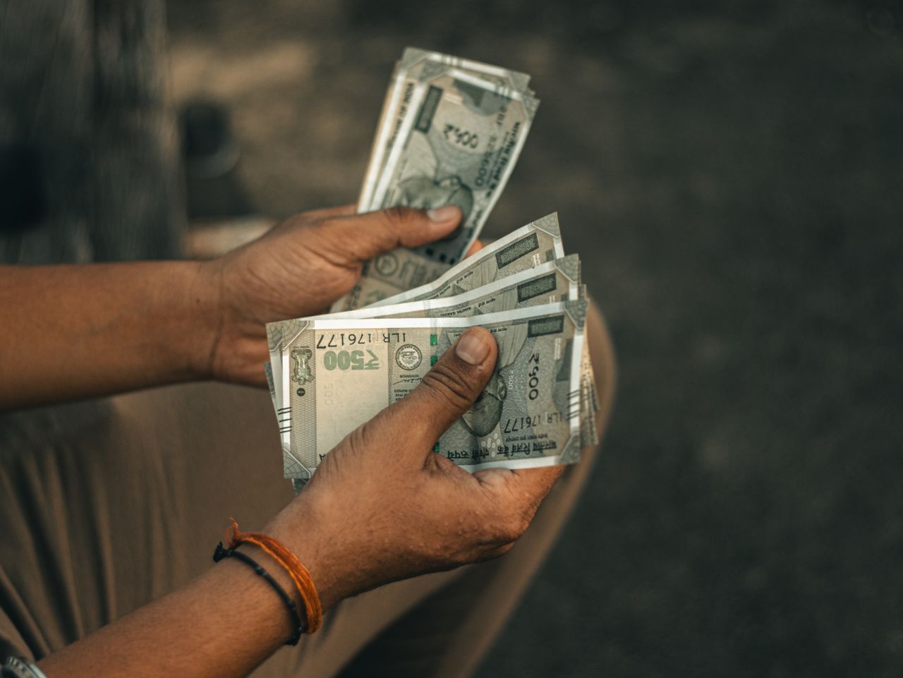 hero-img-02 Close-up of hands holding multiple 500 Indian Rupee notes, representing wealth and financial transactions.